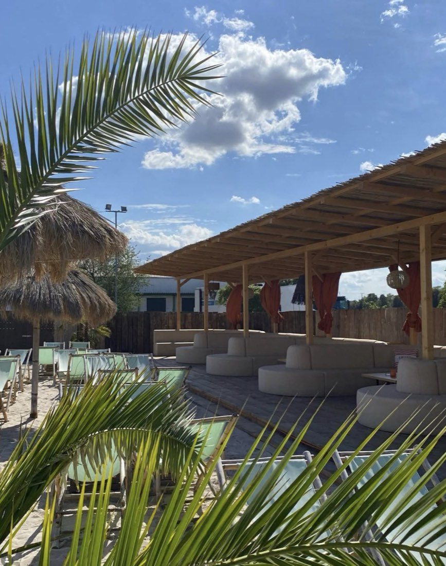 Die Lounge von Hip Island bei Tag, mit Palmen, Sand und Liegestühlen